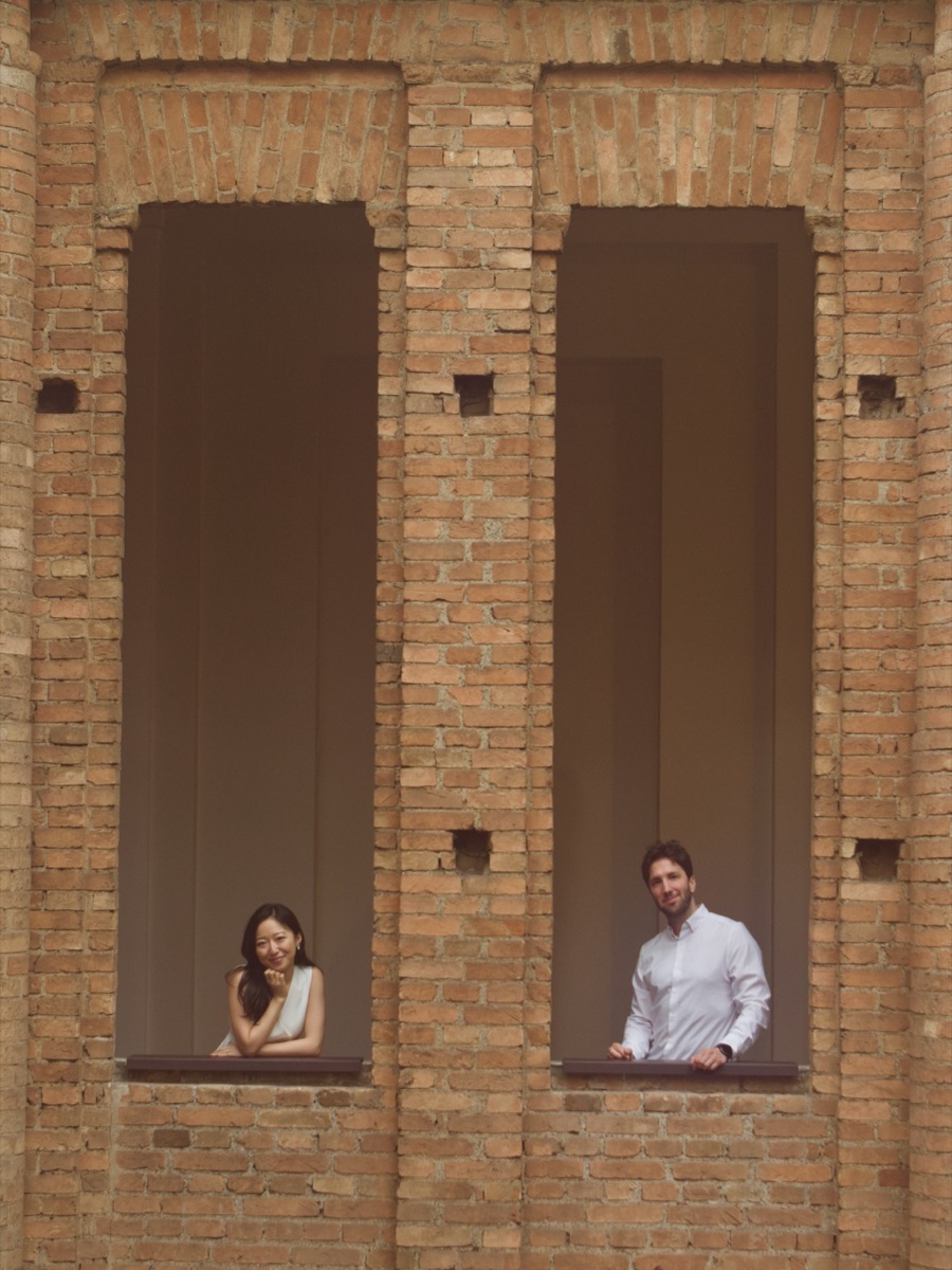 Marika and Beto smiling from twin brick archways